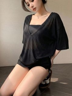 Woman in a black top and shorts kneeling on a wooden floor