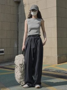Woman in a baseball cap and face mask wearing wide leg pants and a sleeveless top