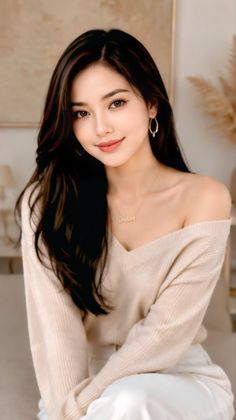 Woman with long dark hair wearing an off-shoulder top and gold jewelry