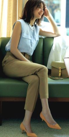 Woman with short hair and a pearl necklace sitting on a green couch
