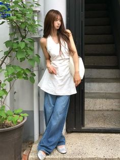 Woman with long hair wearing a white top and wide leg jeans outdoors