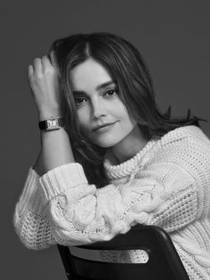Woman with long hair wearing a white cable knit sweater and a watch
