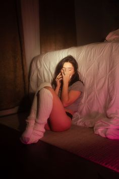 Woman in knee-high socks and underwear sitting on the floor in a dimly lit room