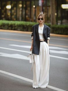 Woman in a blazer, crop top, and wide leg pants standing on a street