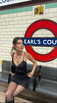 Woman in a black dress and heart necklace sitting in a subway station