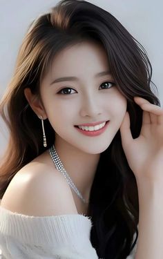 Smiling woman with long dark hair wearing an off-shoulder top and jewelry