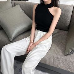 Woman in a black top and white pants sitting on a sofa