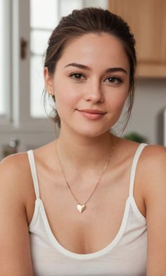 Woman with brown hair in an updo wearing a white tank top and heart necklace