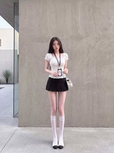 Woman with long dark hair wearing a white top and black mini skirt outdoors