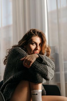 Woman in a gray sweater and white socks with dramatic lighting indoors