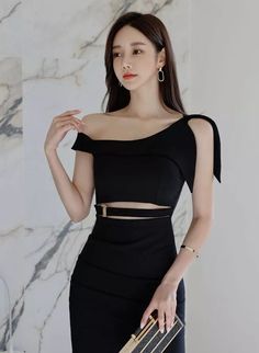 Woman in a black off-shoulder cutout dress holding a clutch bag