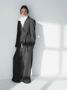 Woman in a pinstripe suit with wide leg pants and a white scarf indoors