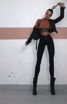 Person in a black leather jacket and jeans with a harness posing indoors