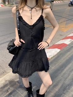 Woman in a black ruffle dress and boots standing outdoors