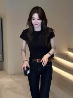 Woman with long dark hair wearing a black t-shirt and jeans indoors