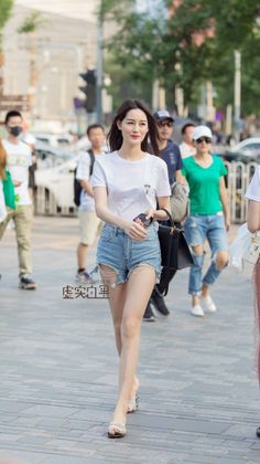 Woman in a white t-shirt and denim shorts walking on a city street