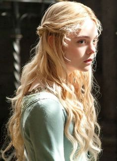 Woman with long blonde wavy hair in a light blue embroidered dress