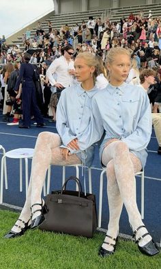 Two women in matching outfits sitting on chairs at an outdoor event