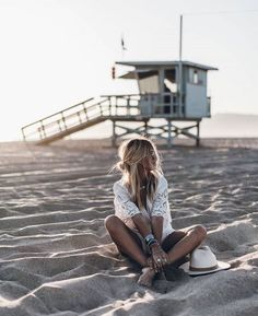 Woman with blonde hair sitting on a sandy beach at golden hour