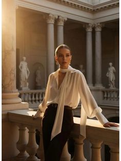 Woman in a white blouse and dark pants in a classical indoor setting