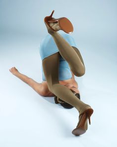 Woman in a blue top and tights with high heels in a gymnastic pose