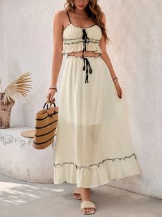 Woman in a cream two-piece outfit with a straw bag outdoors