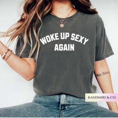 Person wearing a dark t-shirt with "WOKE UP SEXY AGAIN" text and jeans