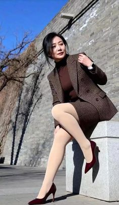 Woman in a tweed suit and high heels sitting outdoors on a sunny day