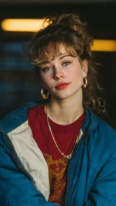 Woman with blue eyes and curly hair in a red t-shirt and blue jacket