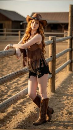 Woman in a cowboy hat and fringe vest leaning on a fence at a ranch