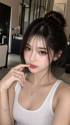 Woman with a messy bun and a white tank top, wearing a heart necklace