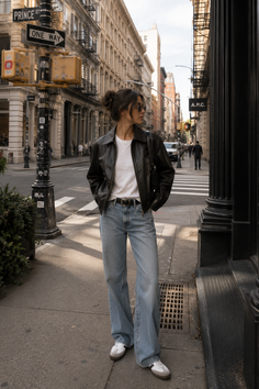 Woman in a leather jacket and wide leg jeans on a city street