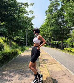 Woman in a white sports bra and black bike shorts outdoors on a sunny day