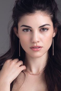 Woman with long dark hair wearing bar earrings and a bar necklace