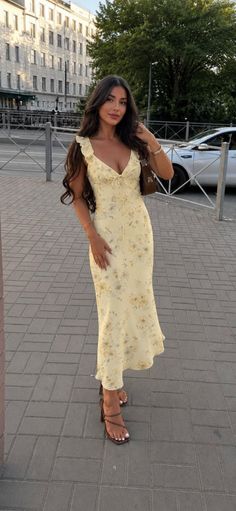 Woman in a yellow floral dress and high heels on a street