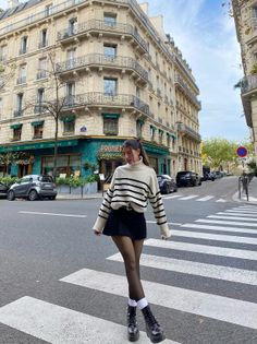 Woman in a striped sweater and mini skirt crossing a city street