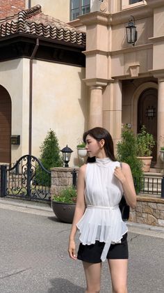 Woman in a white top and black shorts standing outdoors in daylight
