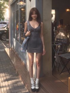 Woman in a gray mini dress and Mary Jane shoes standing on a street
