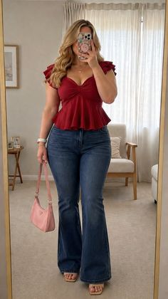 Woman with blonde hair in a red top and flared jeans holding a pink handbag