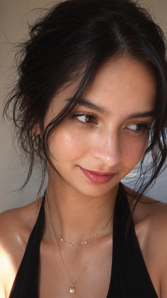 Woman with dark hair and gold jewelry looking to the side