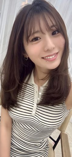 Woman with long brown hair and bangs wearing a striped top and smiling