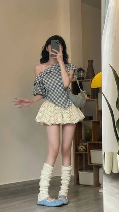 Woman in a plaid top and polka dot skirt taking a mirror selfie