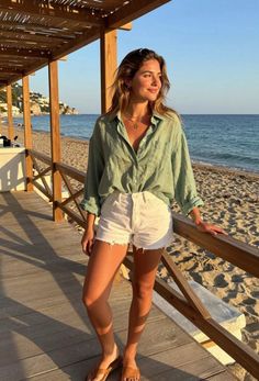 Woman in a green shirt and white shorts on a beach boardwalk at golden hour