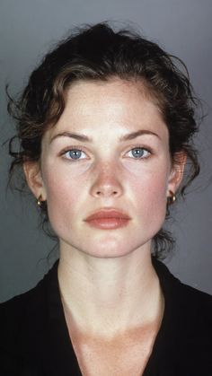 Woman with blue eyes and dark curly hair wearing gold hoop earrings