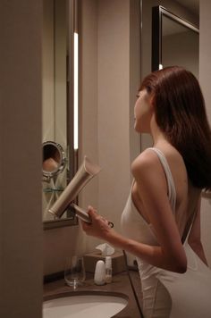 Woman in a white dress drying her hair in a bathroom