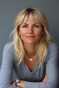 Woman with blonde hair and a v-neck shirt looking directly at the camera