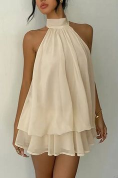 Woman in a cream-colored halter mini dress with gold jewelry