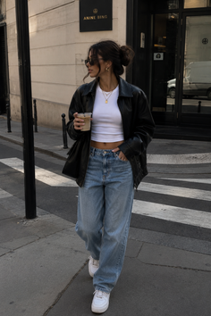 Woman in a leather jacket and baggy jeans walking on a city street