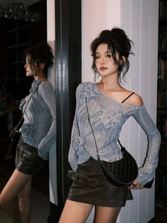 Woman in an off-shoulder top and leather skirt posing indoors