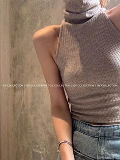 Upper body of a person wearing a ribbed turtleneck sleeveless top and denim jeans